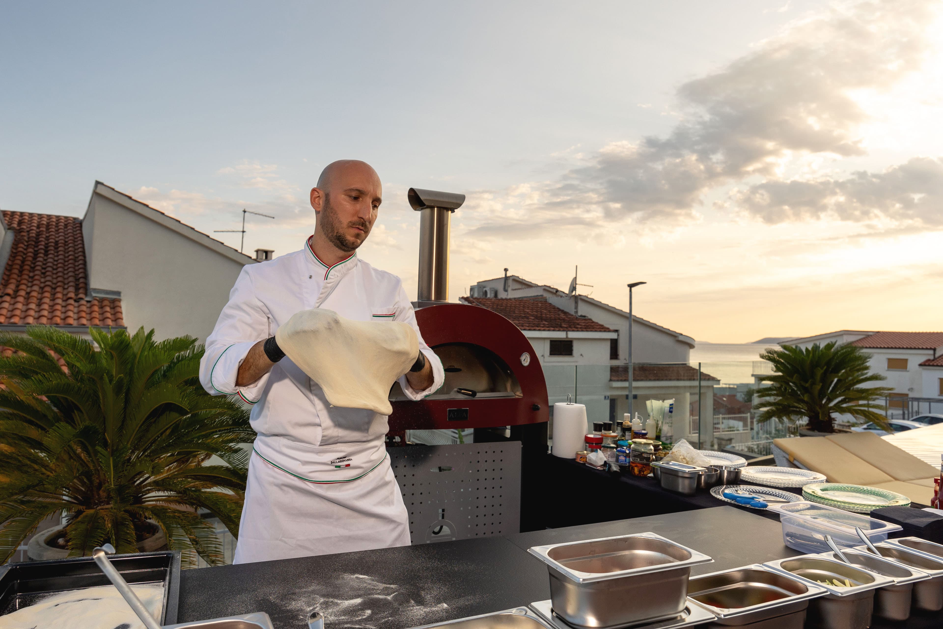 Chef stretching pizza dough at the outdoor wood-fired oven